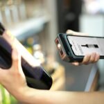 Close-up of a person scanning a wine bottle with a portable scanner in a store.